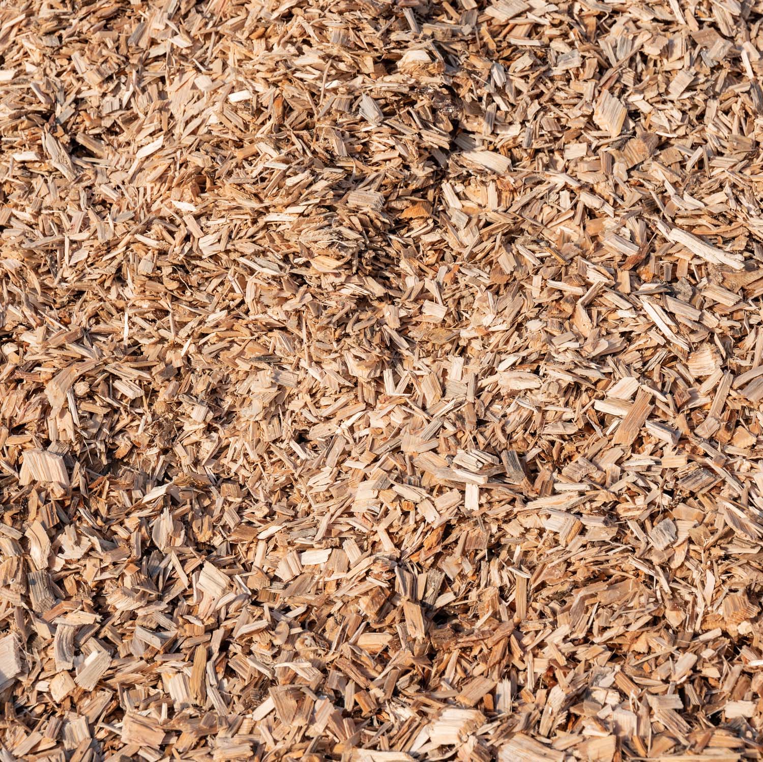 Holzhackschnitzel Nahaufnahme von Holzhackschnitzeln, die in verschiedenen Braun- und Beigetönen gehalten sind. Die Holzhackschnitzel haben eine unregelmäßige Form und Größe, was eine natürliche, organische Textur erzeugt.